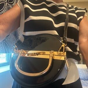 Mezon FASHION ROUND FRAMED BLACK PATENT BOX
BAG WITH LONG STRAP & GOLD ACCENTS